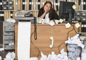 Messy office desk with disgruntled office worker
